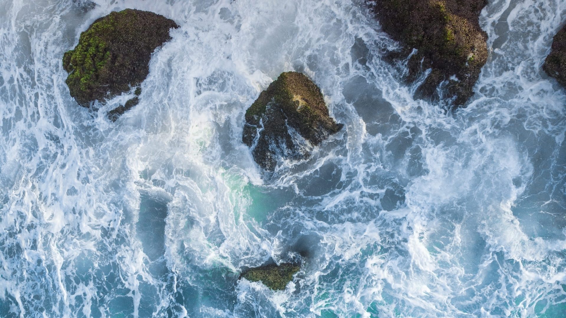 vertical-overhead-aerial-shot-wavy-blue-sea-against-rocks (1) (1) (1)